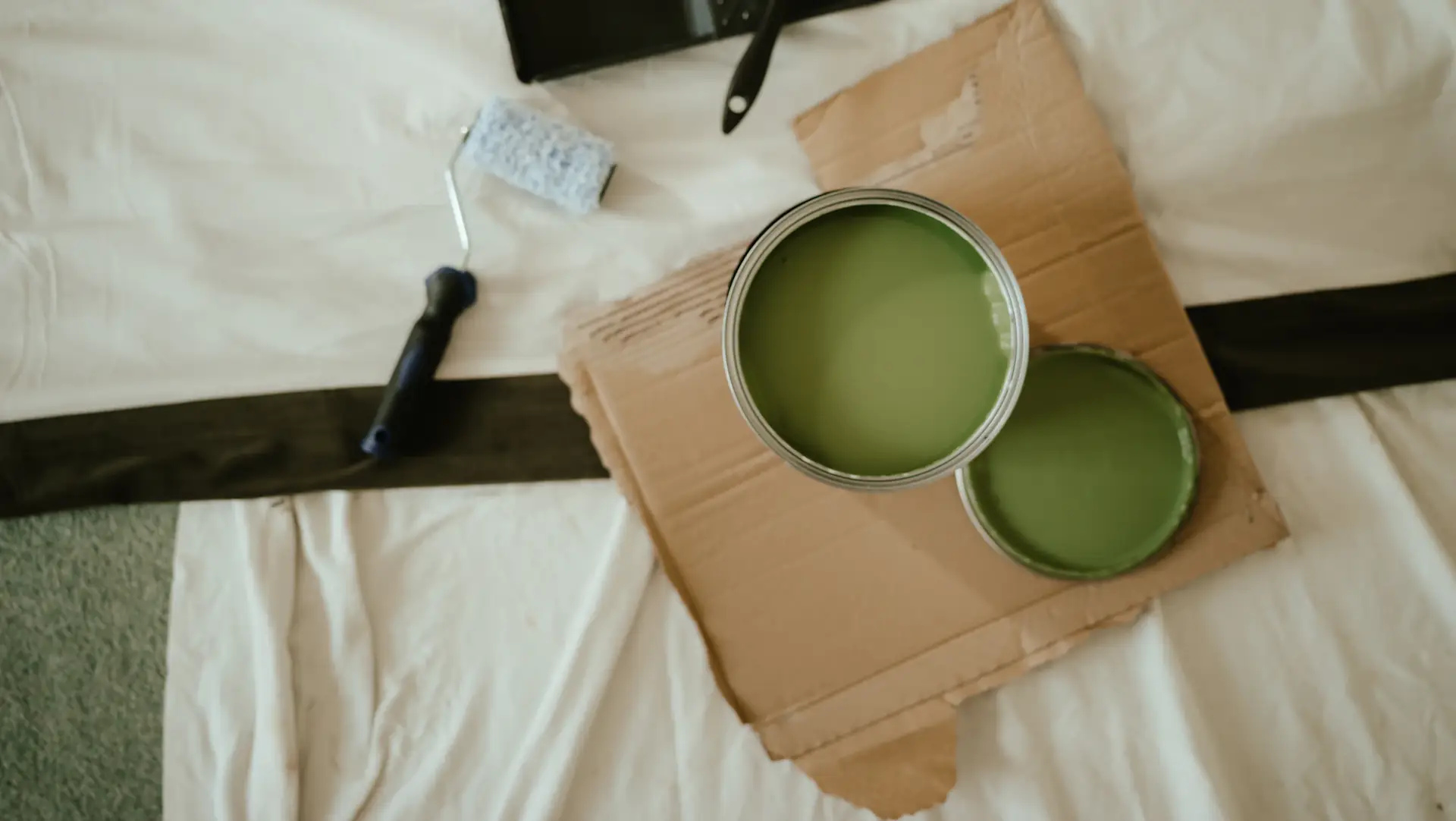 Paint tins and a roller on a drop sheet
